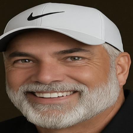 Middle-aged man with gray beard wearing white Nike cap, smiling at camera against dark background